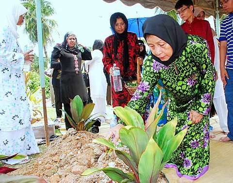 Isteri Allahyarham Noriah Ishak menabur air mawar keatas pusara Allahyarham Aimi Jarr.Foto The Star Oleh MUHAMMAD AKIF   