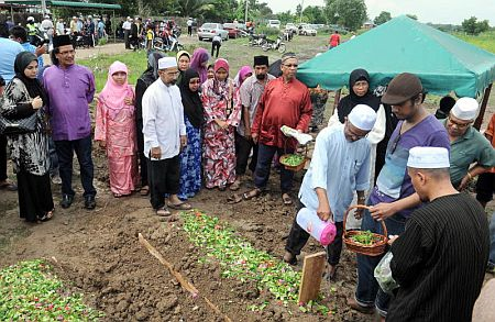 Imuda (dua dari kiri) melihat ahli keluarga Ahmad Busu menabur bunga ke atas pusara Allahyarham.