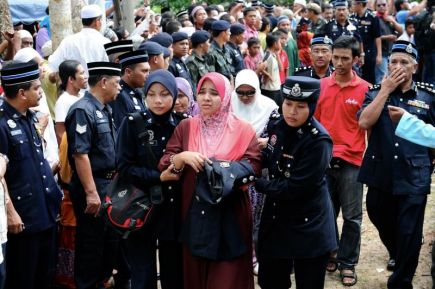 Isteri allahyarham Inspektor Zulkifli Mamat, Nor Aziah Nor, 27, dipapah anggota polis sewaktu menyiram air mawar di pusara suaminya yang terkorban di Lahad Datu di Tanah Perkuburan Islam Gong Bayor di Besut, Terengganu pada Sabtu.-Foto BERNAMA