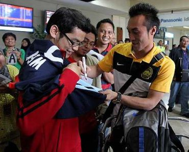 Khairul Fahmi melayan salah seorang penyokong Malaysia ketika tiba di Lapangan Terbang Soekarno-Hatta, Jakarta, Indonesia, Isnin. GLENN GUAN/The Star