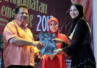 Menteri Wilayah Persekutuan, Datuk Seri Tengku Adnan Tengku Mansor (kiri) menyampaikan anugerah kepada Iznariza Che Izham (kanan) dari Pejabat Pelajaran Wilayah Keramat pada Majlis Penyampaian Anugerah Perkhidmatan Cemerlang 2012 Jabatan Pelajaran Wilayah Persekutuan Kuala Lumpur di Menara Lembaga Pertubuhan Peladang (LPP) di Kuala Lumpur, Selasa.  Foto BERNAMA