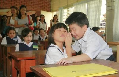 Lim Kai Xiang, 7, berbisik sesuatu kepada kawan barunya, whispering Myra Lim, 7, (kanan) sambil diperhatikan ibu bapa mereka di SJKC Hun Bin, Tanjung Tokong.
