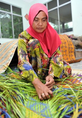 Asiah sedang membuat anyaman tikar untuk dijual.